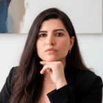 Close-up do rosto da advogada previdenciarista Lizarb Guimarães, com a mão no queixo e expressão séria, vestindo blazer preto.